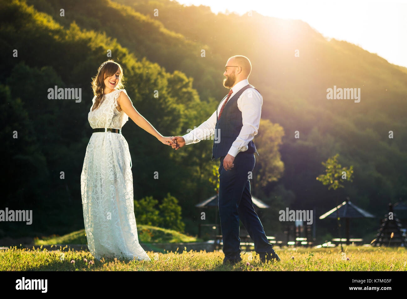 Bride and Groom holding hands at romantique coucher de soleil Banque D'Images