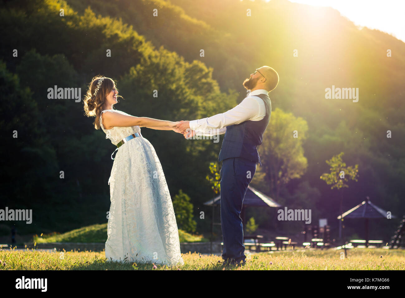 Bride and Groom holding hands at romantique coucher de soleil Banque D'Images