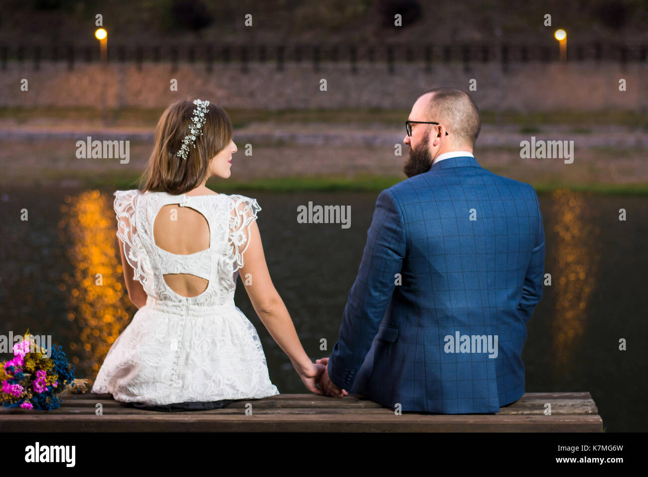 Bride and Groom assis au bord du lac dans la nuit Banque D'Images