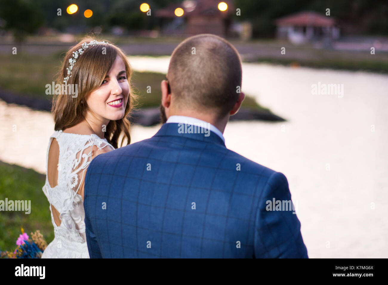 Bride and Groom assis au bord du lac à la soirée Banque D'Images
