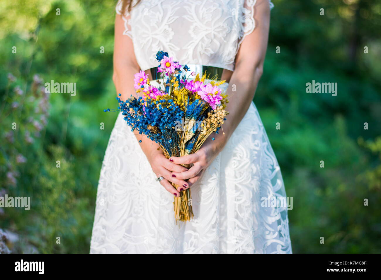Bride holding bouquet coloré dans la forêt à l'extérieur Banque D'Images