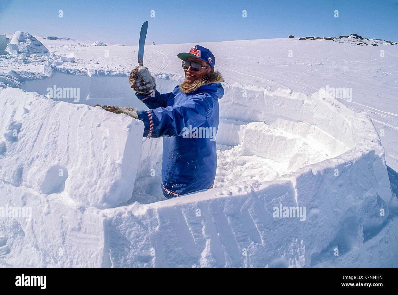 Aîné inuit homme, vêtu de vêtements modernes, s'appuie l'Arctique igloo en sculptant des blocs de neige et de les placer avec soin. c'est un abri traditionnel toujours utilisé par certains Inuits aujourd'hui Banque D'Images