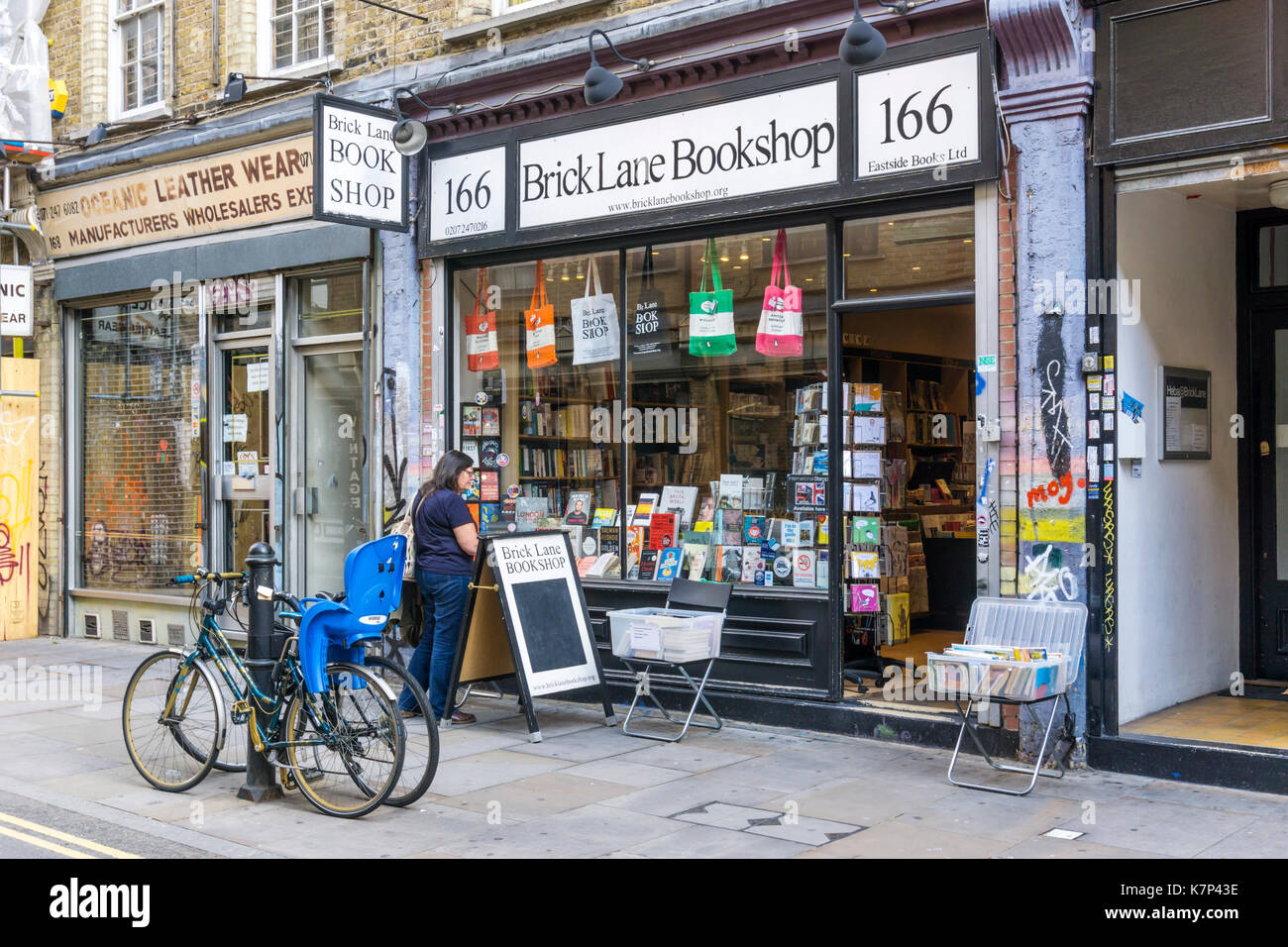 Femme de navigation dans la fenêtre de la librairie Brick Lane à Whitechapel. Banque D'Images