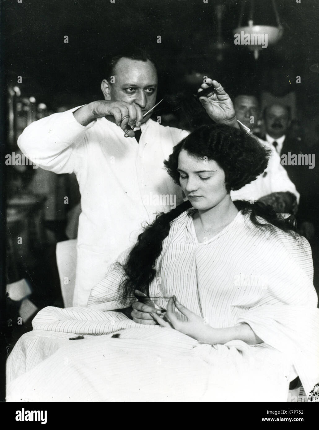 1920 - une jeune femme se faire 'cheveux' se balancent dans un salon de coiffure pour hommes. Banque D'Images