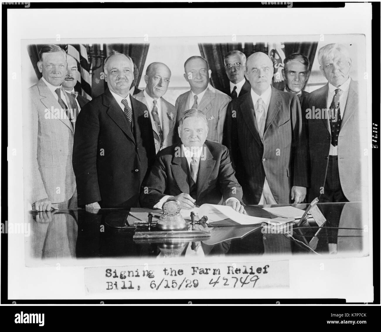 Le président Herbert Hoover (assis, au centre) signe le projet de loi de secours agricole, entouré par les dirigeants du Congrès y compris Nicholas Longworth, Président de la Chambre des Représentants, à gauche de Hoover, Washington, DC, 06/15/1929. Banque D'Images