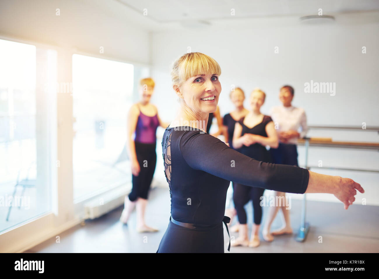 Senior woman doing ballet en un studio de danse avec un groupe d'amis dans l'arrière-plan Banque D'Images
