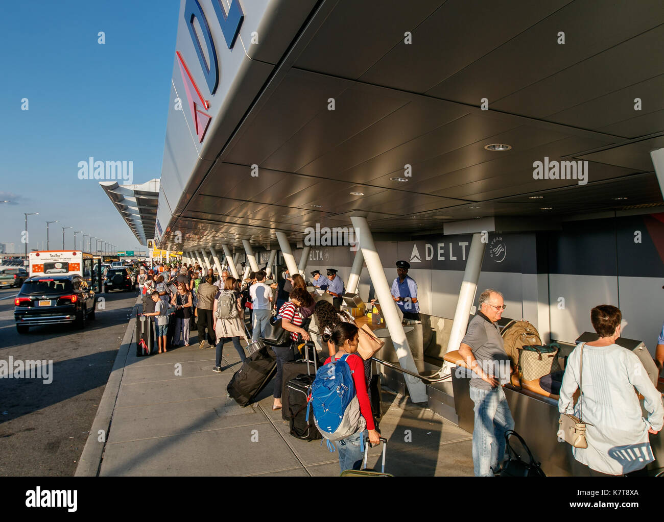 Sur le trottoir, les gens vont de l'enregistrement en cas de vols de ligne aérienne de Delta à l'aéroport JFK. Banque D'Images