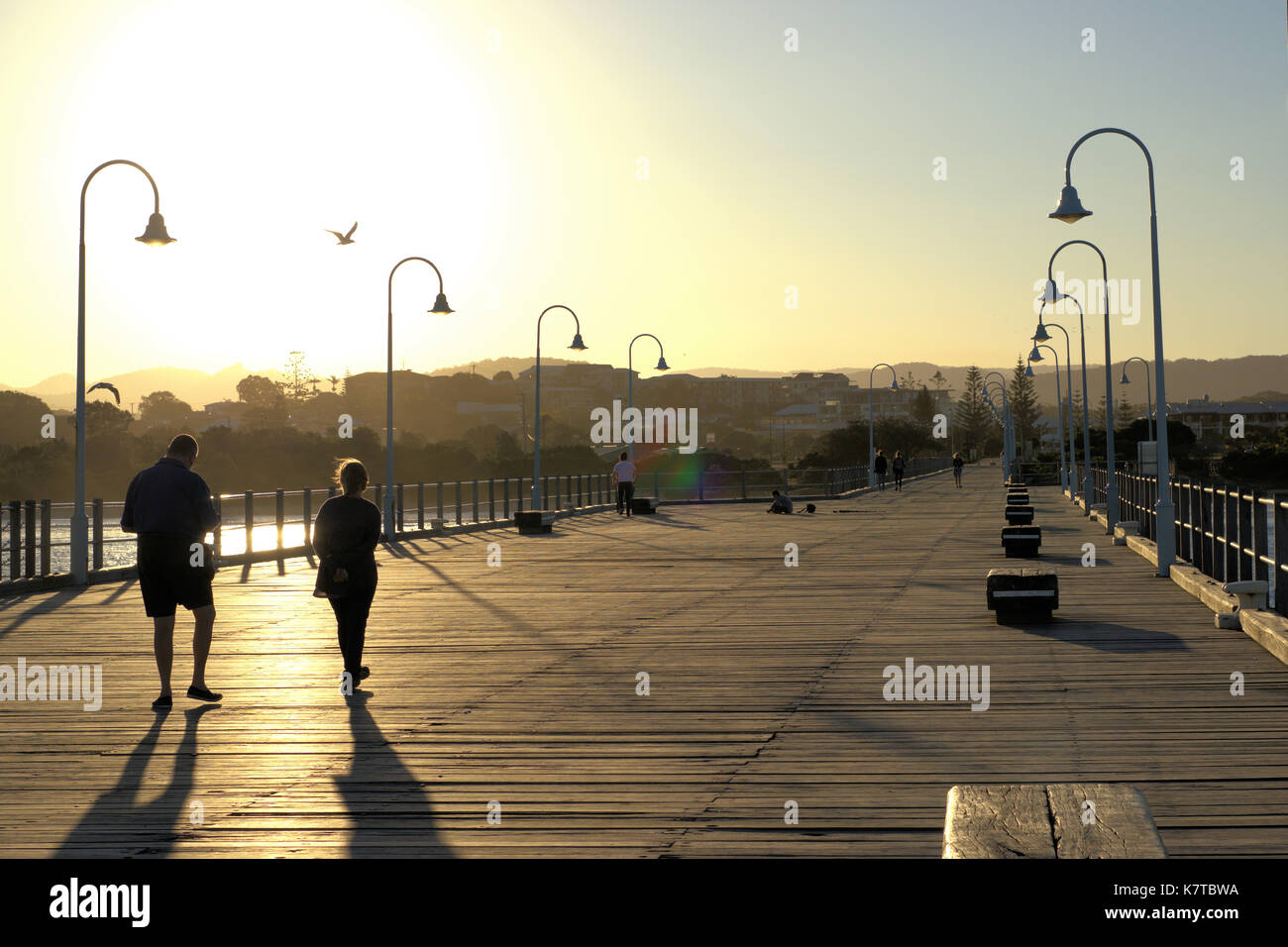 Heure d'or de l'Australie. Coucher du soleil vu de la jetée à Coffs Harbour, destination de vacances, de l'Australie. Les gens de walking street, banc en bois, etc Banque D'Images