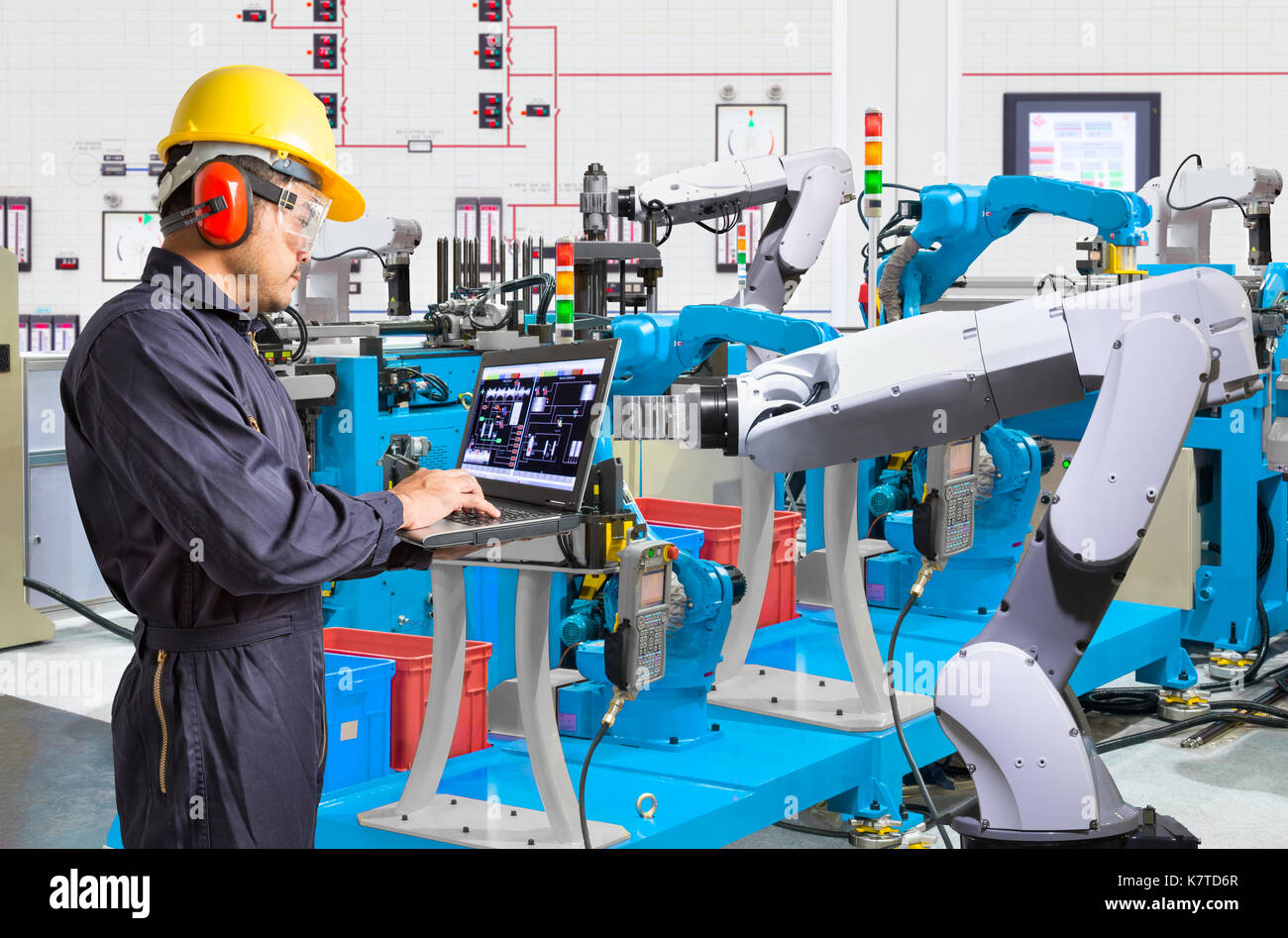 Ordinateur portable à l'aide de l'ingénieur pour l'entretien de la machine-outil main robotisée automatique à l'usine de fabrication industrielle Banque D'Images