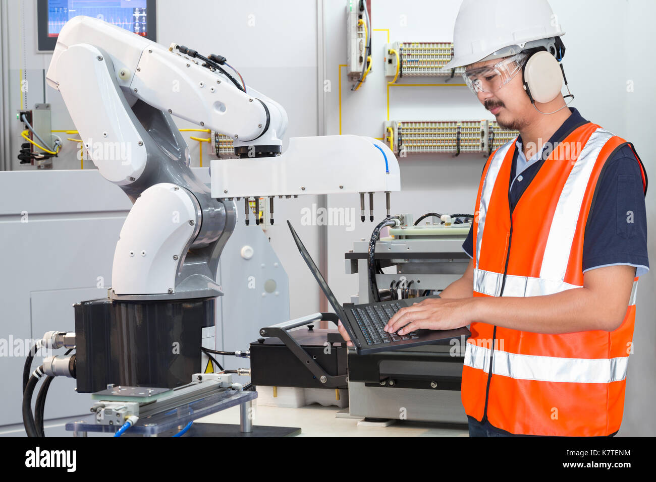 Ordinateur portable à l'aide de l'ingénieur pour l'entretien de la machine-outil automatique main robotique dans l'industrie, usine à puce électronique 4.0 concept Banque D'Images