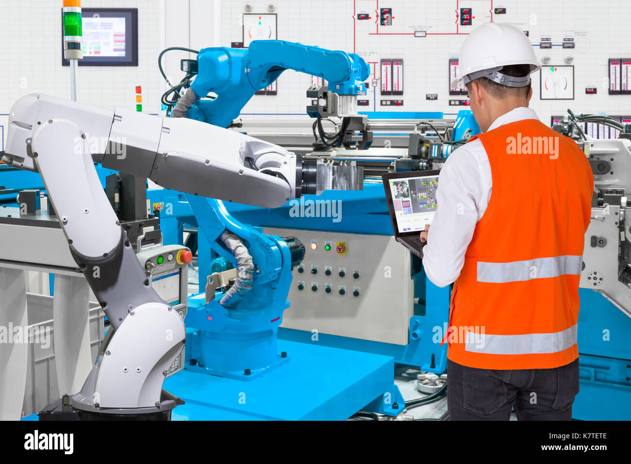 Ordinateur portable à l'aide de l'ingénieur pour l'entretien de la machine-outil automatique main robotique industrielle à l'usine de fabrication, de l'industrie 4.0 concept Banque D'Images