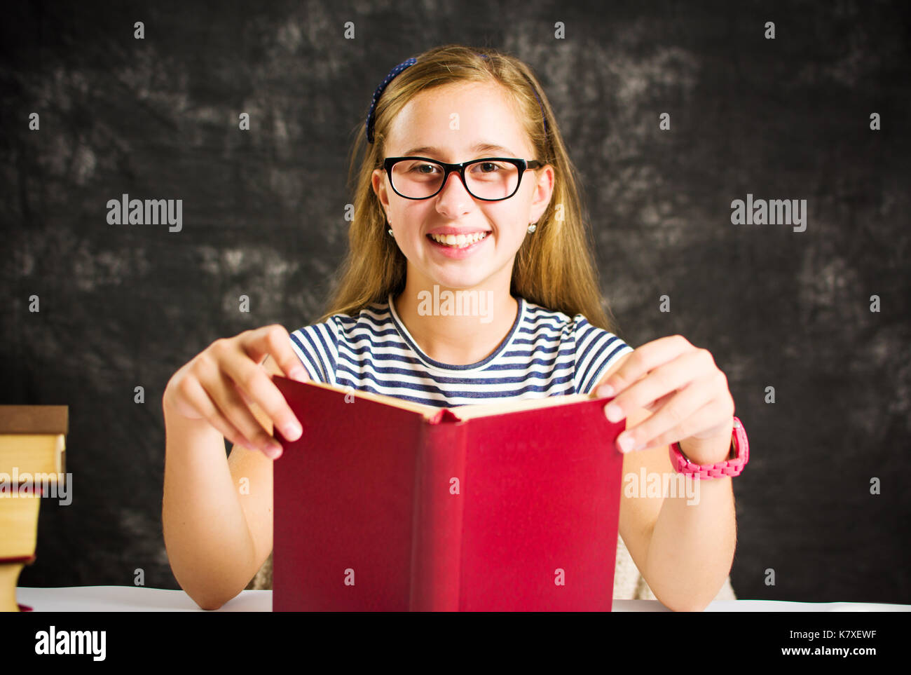 Happy girl la lecture d'un livre à la maison rouge Banque D'Images