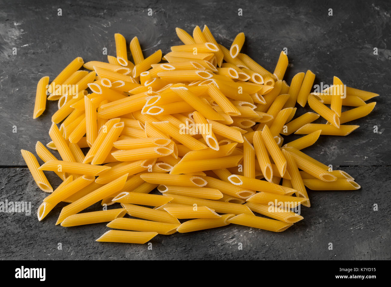 Tas de matières, non cuit, sec pâtes penne noodles sur arrière-plan du tableau noir Banque D'Images