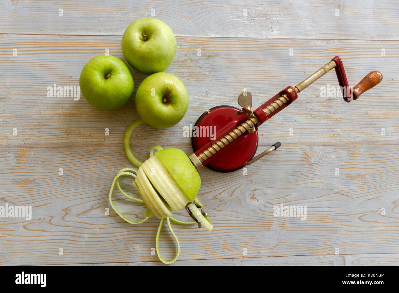 La pomme verte Granny Smith apple mécanique avec un carottier slicer peeler et rustique sur les planches de bois. Banque D'Images