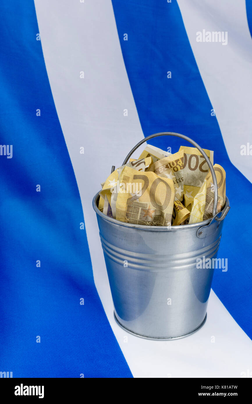 Drapeau grec avec un seau en métal de 200 billets en euros. Pour la crise financière grecque et le sauvetage, l'allégement de la dette grecque, la crise économique grecque, la récession grecque. Banque D'Images