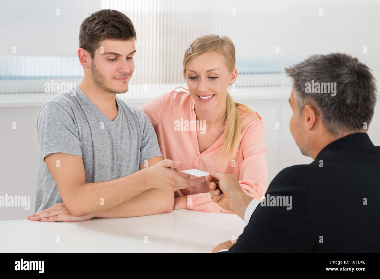 Mature Businessman Carte de visite donnant à Young Couple In Office Banque D'Images