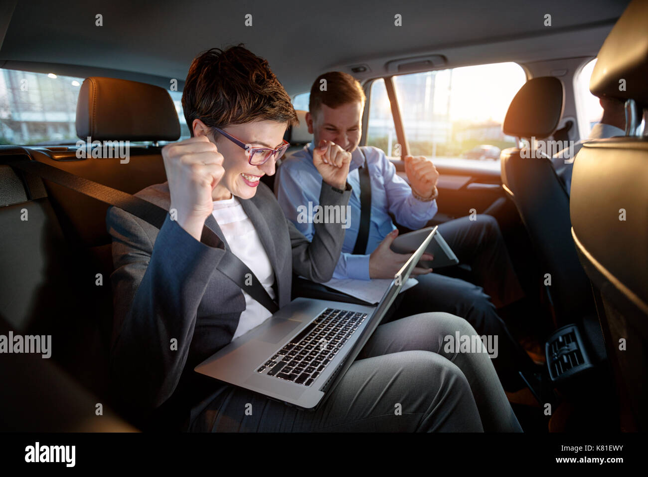 Heureux businesspeople looking at laptop in car en voyage d'affaires Banque D'Images