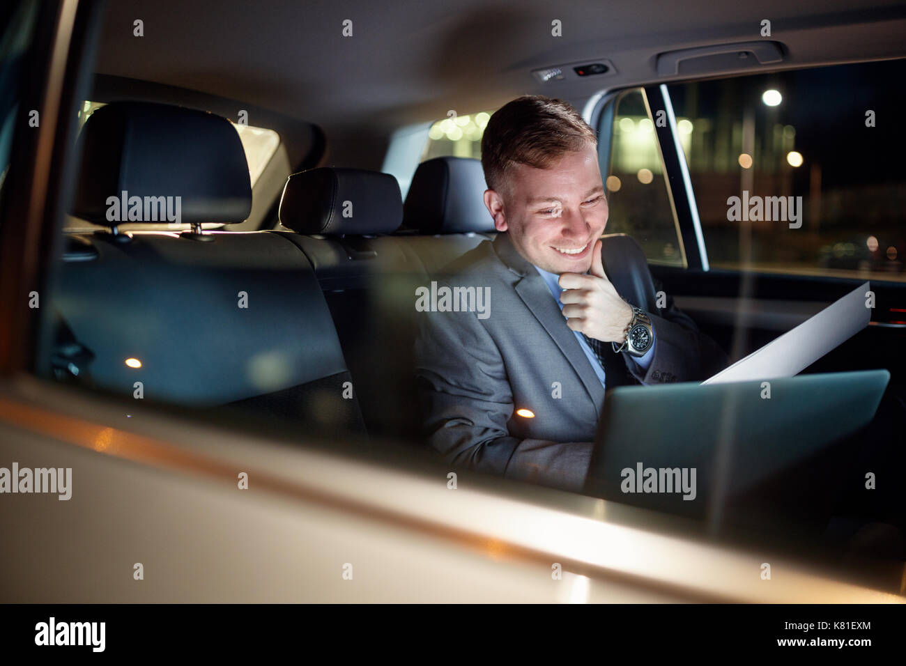 Smiling businessman in déménagement Location de travailler des heures supplémentaires sur son ordinateur portable Banque D'Images