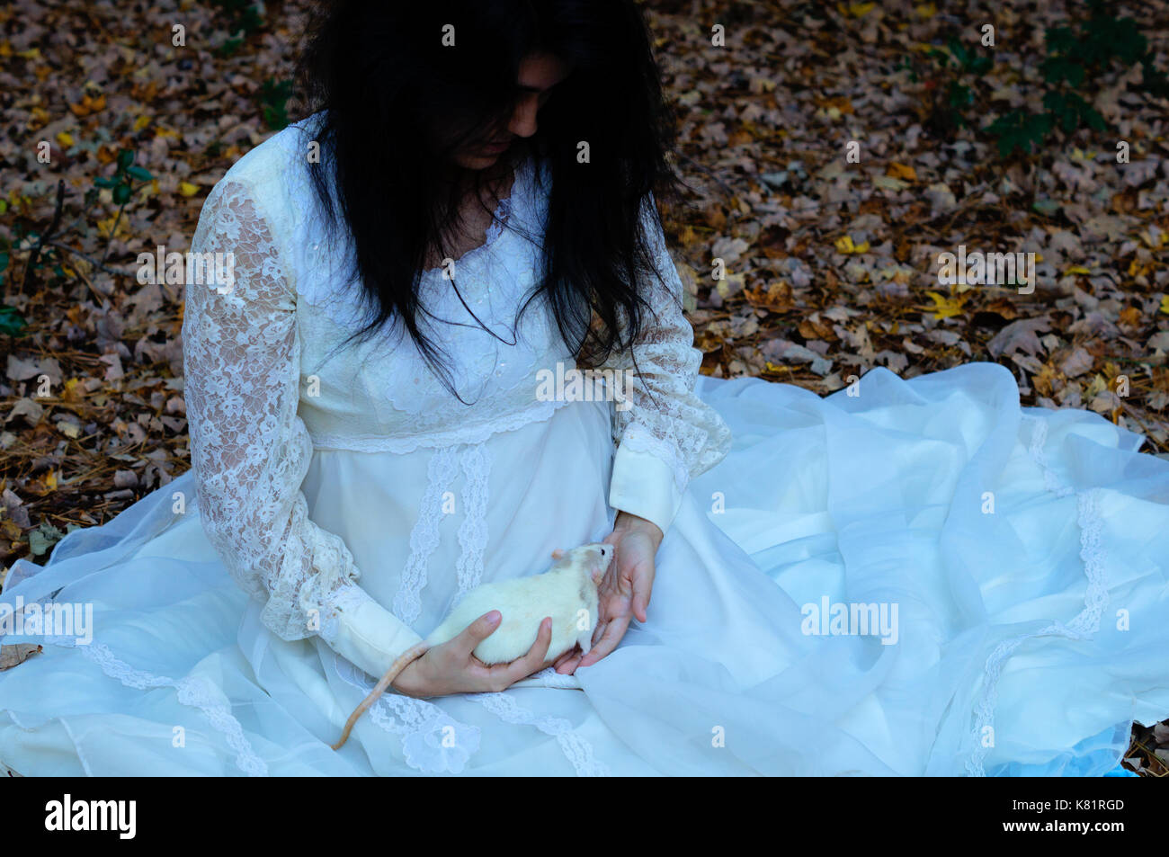 Young girl holding a white rat dans une robe blanche Banque D'Images