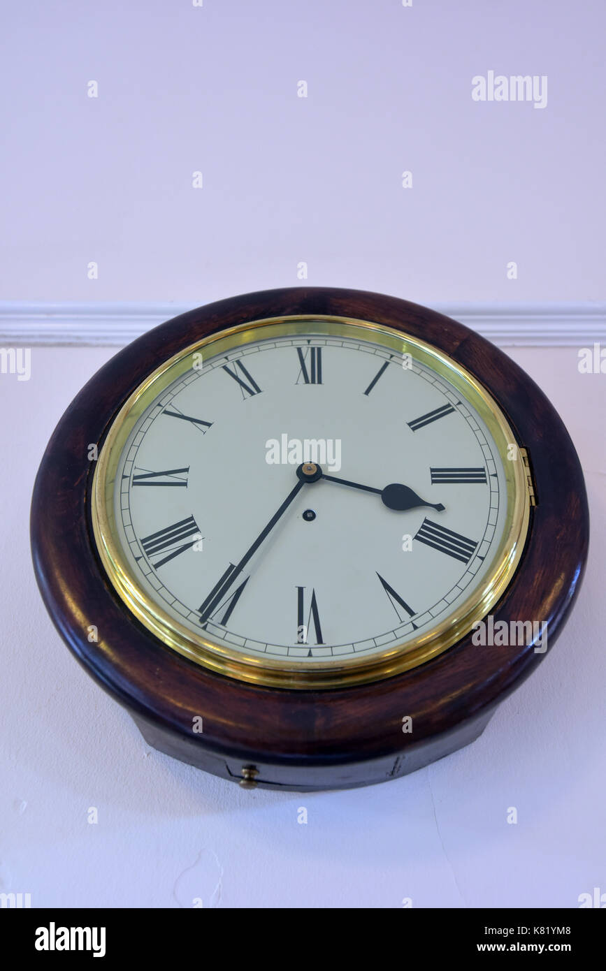 Une ancienne gare en bois ronde horloge sur le mur d'une salle d'attente avec peint bord laiton au verre composer. Gare ferroviaire principale de wall clock Banque D'Images