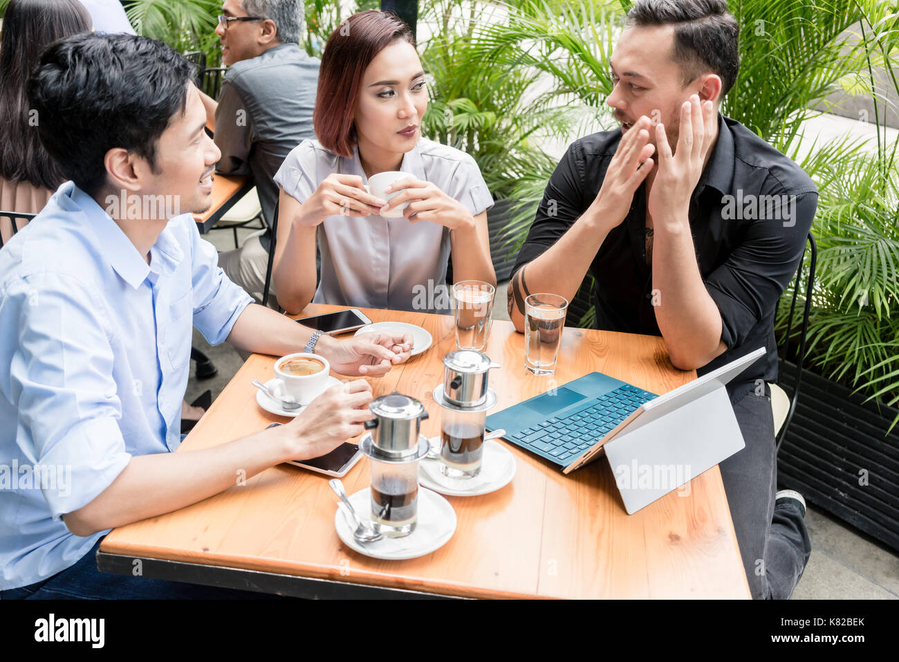 Café vietnamien servi sur la table des trois amis à l'extérieur Banque D'Images