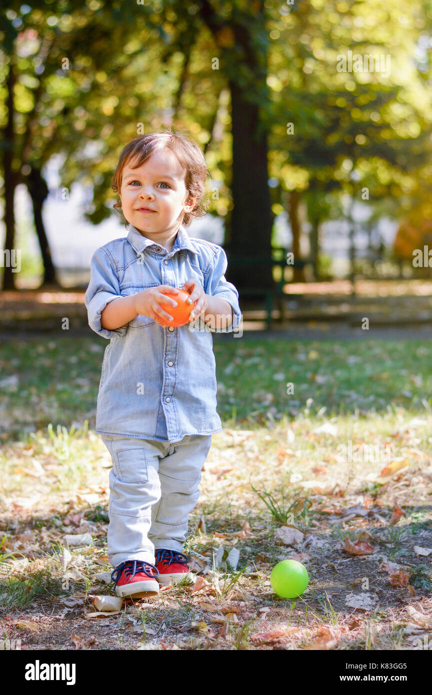 Adorable enfant âgé d'un an dans le parc à jouer avec son jouet Banque D'Images