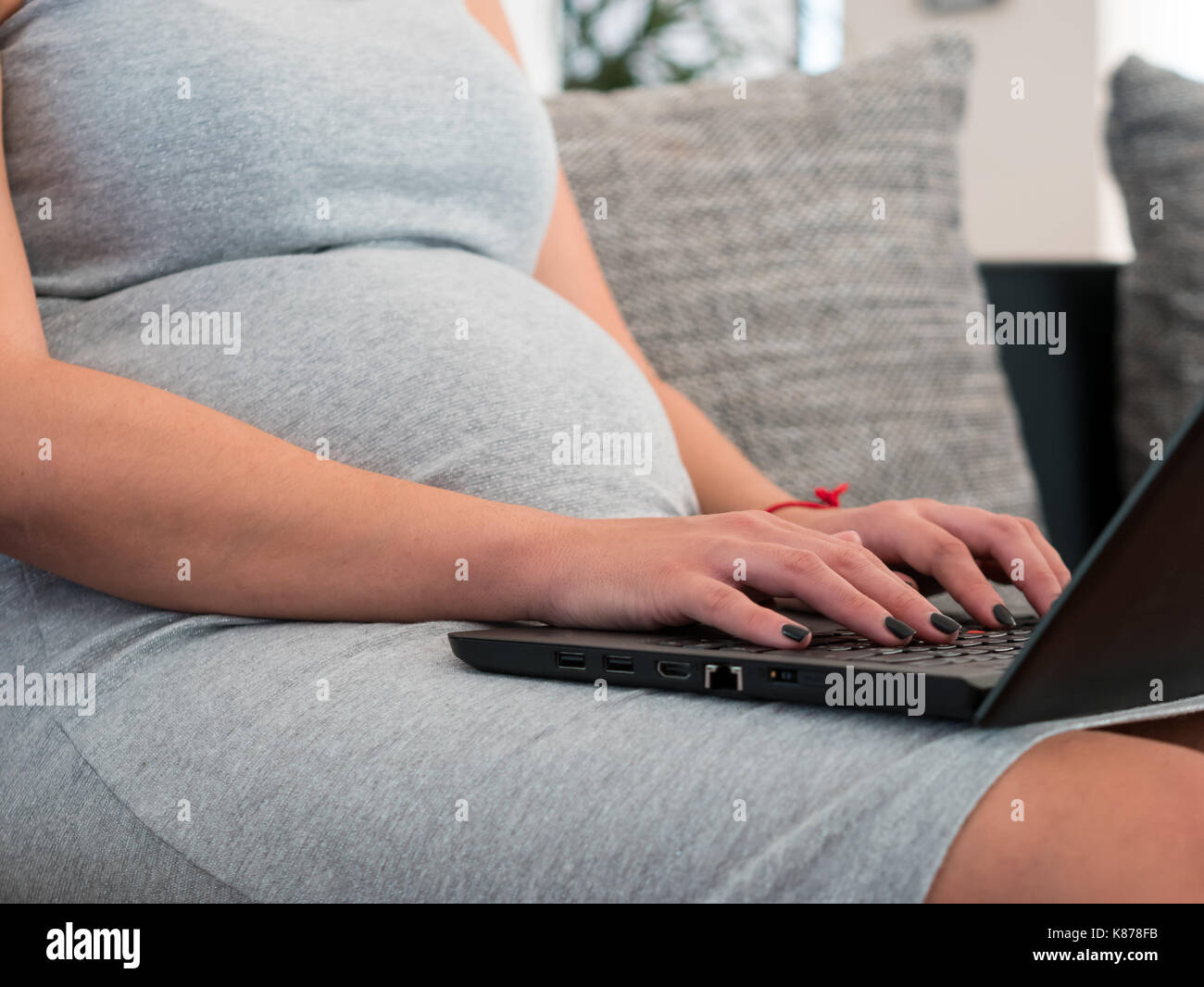 Jeune femme enceinte en ligne de travail à la maison sur un ordinateur portable Banque D'Images