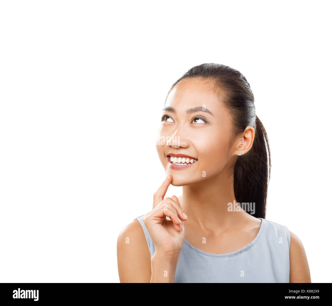 Jeune femme asiatique attrayant de rêver avec le doigt près de menton. Pensive girl smiling, portrait. Portrait of female model close up isolated on white Banque D'Images