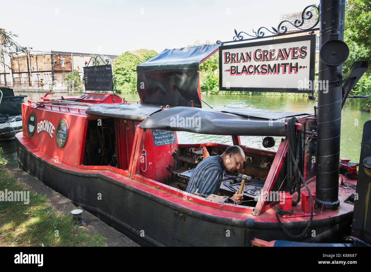 Forgeron au travail sur son narrowboat amarré sur le canal. Banque D'Images