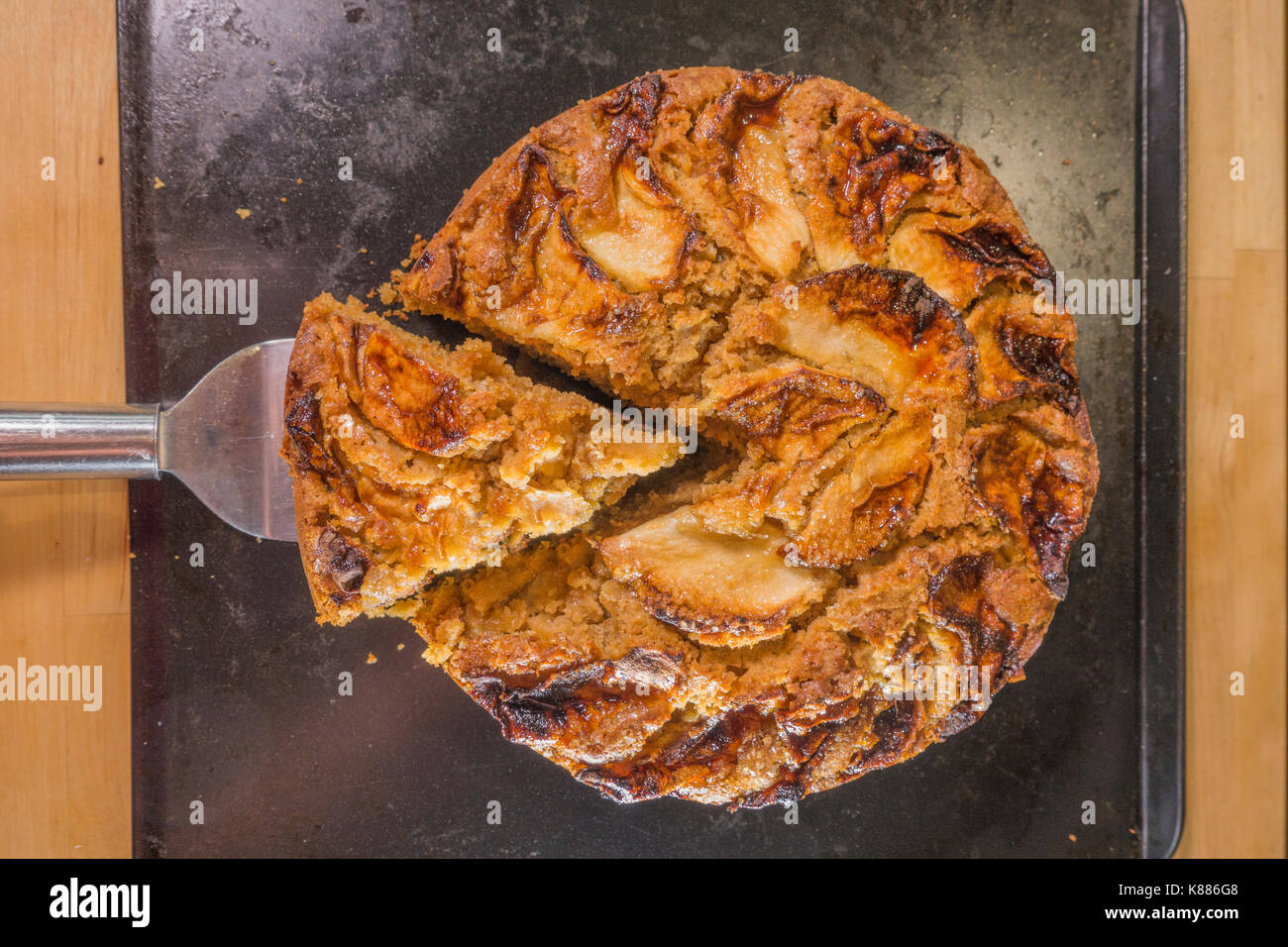 Une coupe triangulaire de gâteau aux pommes épicées, de refroidissement sur une plaque de cuisson dans une cuisine, de l'étuve. Angleterre, Royaume-Uni. Banque D'Images