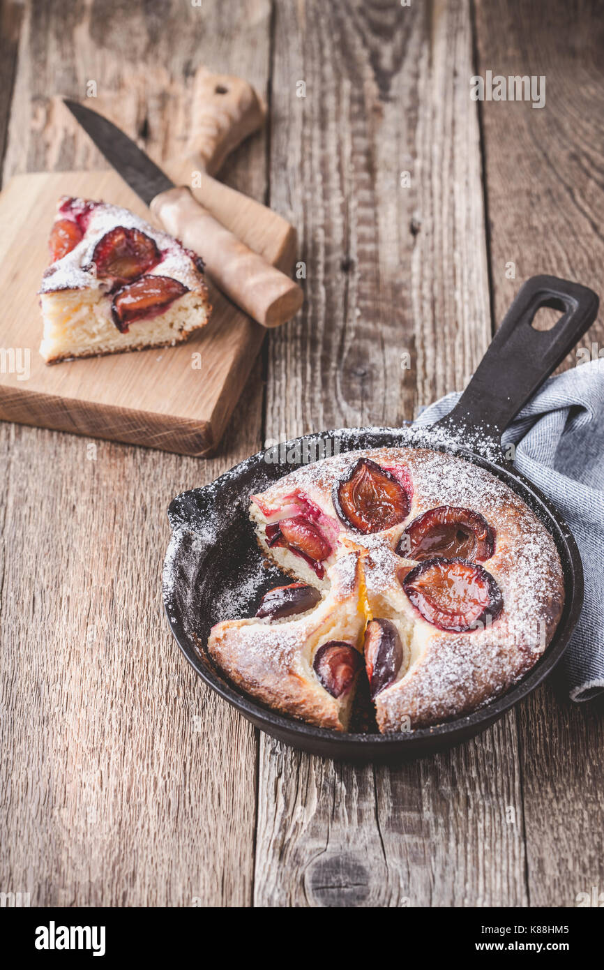 Tarte aux fruits d'été avec des prunes en fonte poêlon sur table en bois rustique Banque D'Images