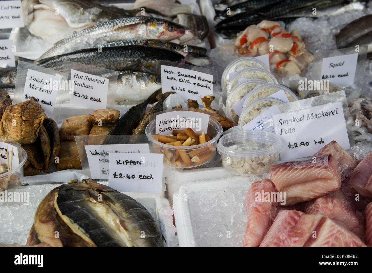 Les poissons, les pétoncles et les filets fumés en vente sur un marché à Londres avec des échantillons gratuits offerts à déguster Banque D'Images