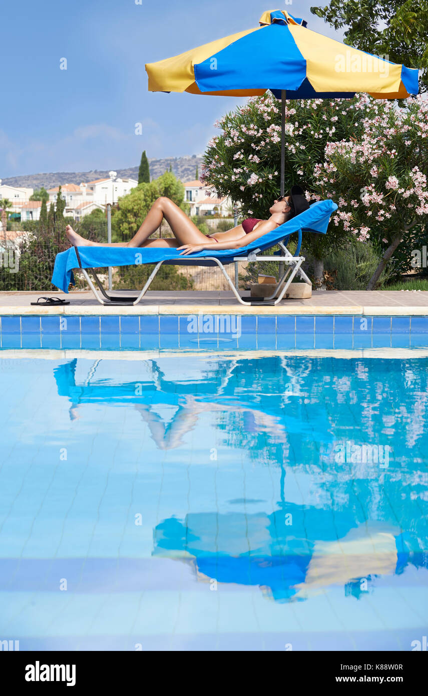 Jeune femme en bikini pour bronzer sur les transats de piscine Banque D'Images