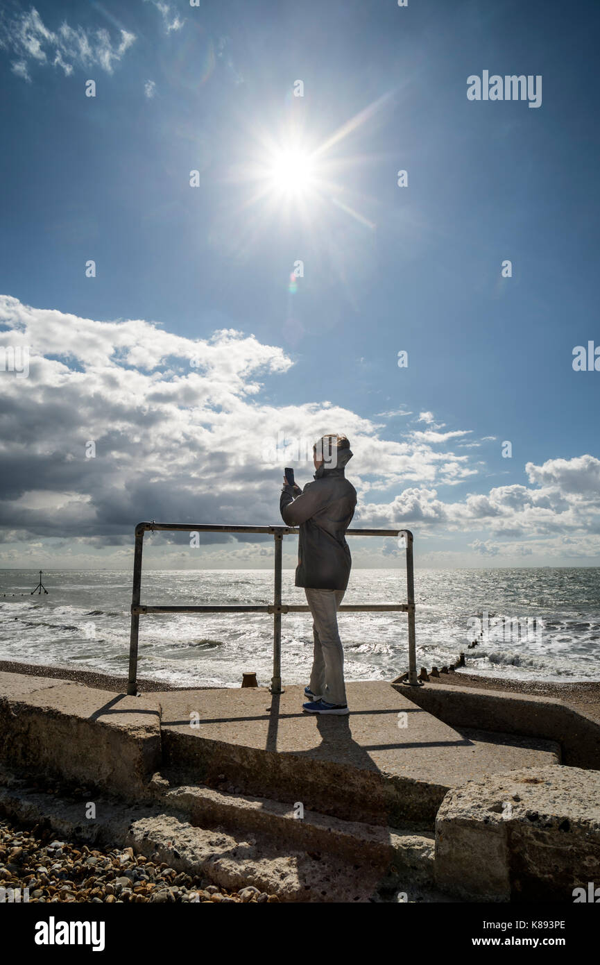 Woman taking a photo sur son téléphone portable par la mer Banque D'Images