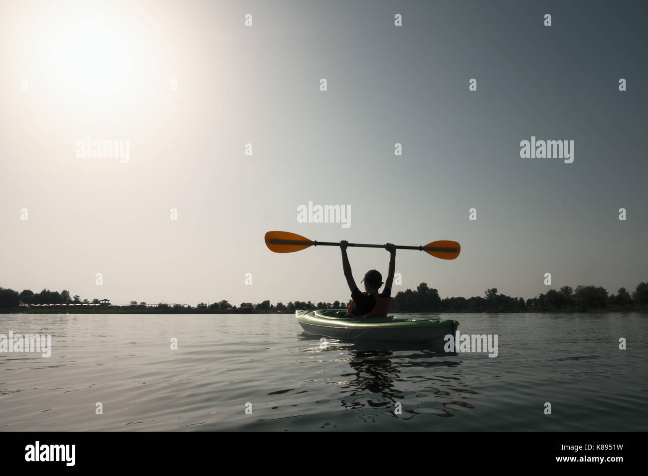 Garçon en veste verte sur kayak. journée ensoleillée sur le lac merveilleux. L'heure d'été Banque D'Images