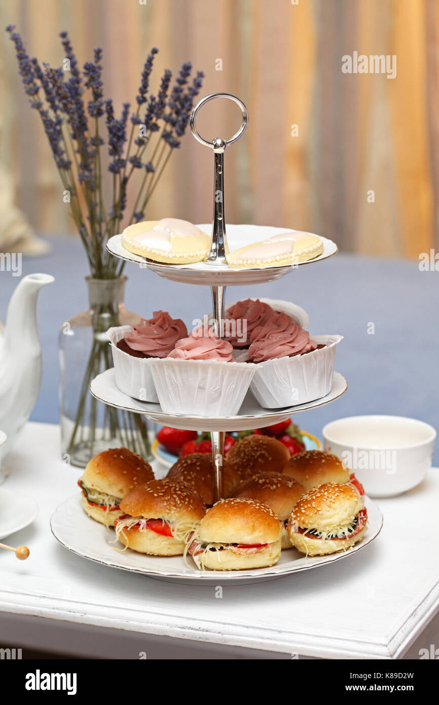 Des sandwiches et des gâteaux sur tiered plateau de service à table basse Banque D'Images