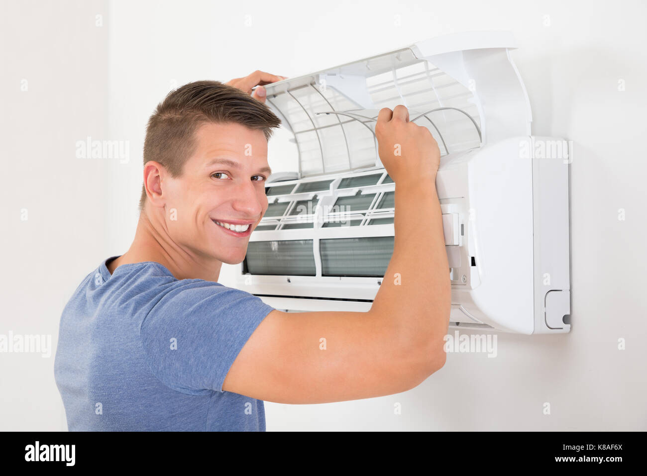 Jeune homme heureux du système de climatisation nettoyage à domicile Banque D'Images