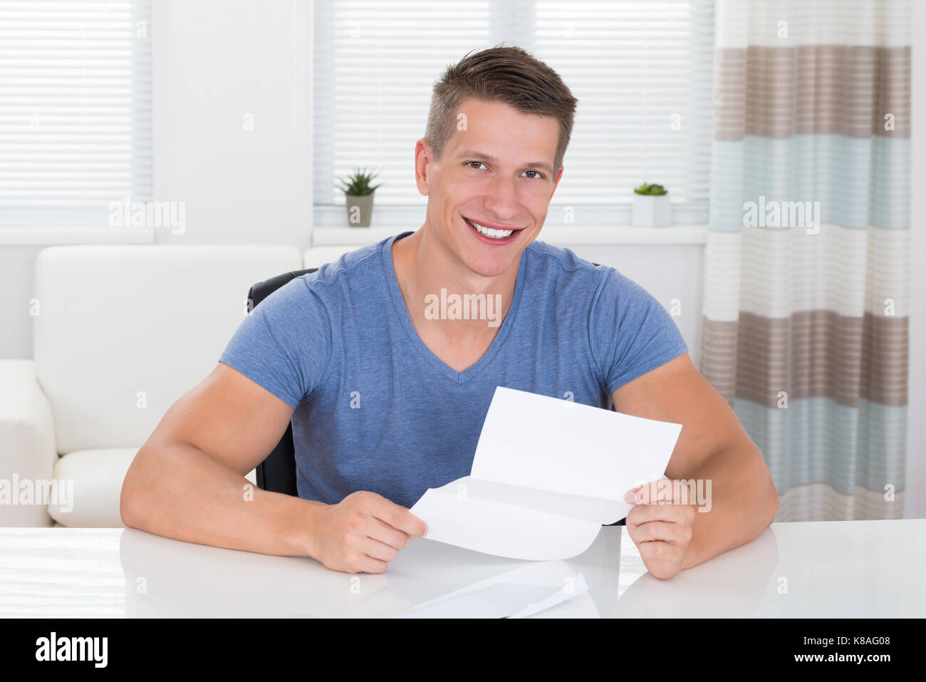 Heureux jeune homme lire une lettre envoyée au bureau Banque D'Images