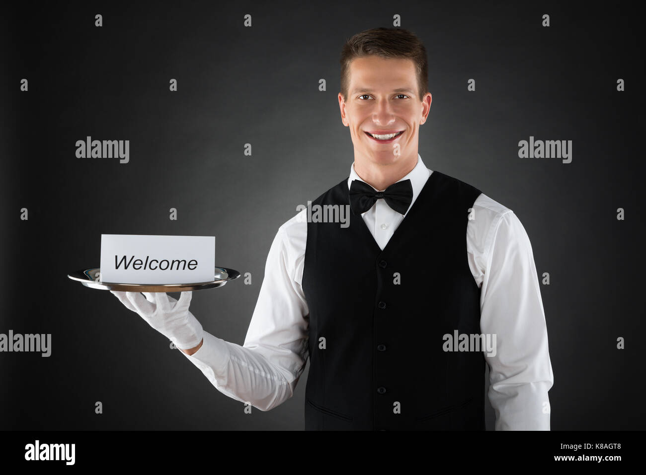 Portrait of Young Waiter Holding Plaque avec texte Bienvenue sur carte Banque D'Images