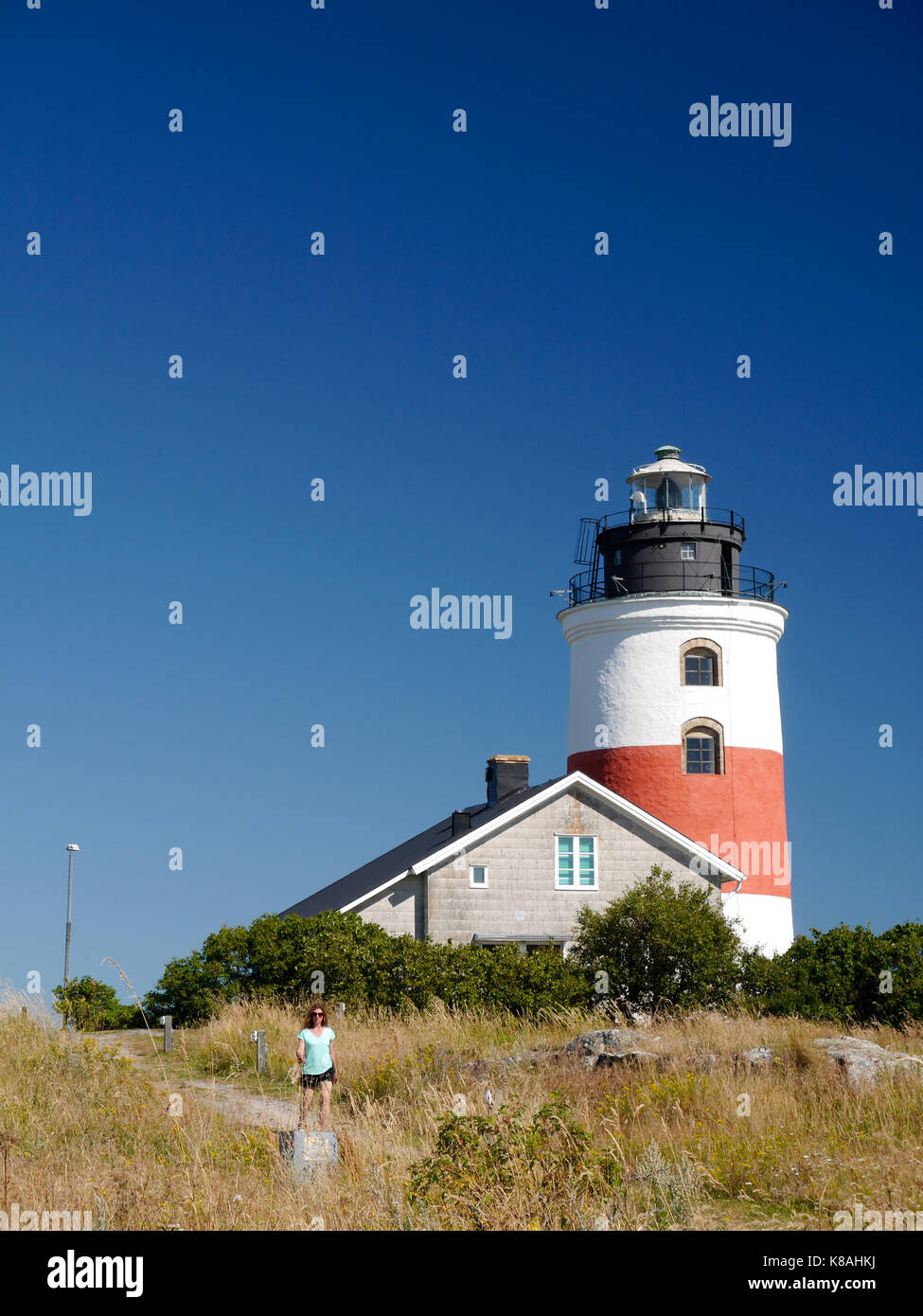 Femme marchant devant le phare de Söderarm, à l'extérieur de Räfsnäs, Gräddö, Rådmansö dans l'archipel de Roslagen, Stockholm, Suède. Banque D'Images