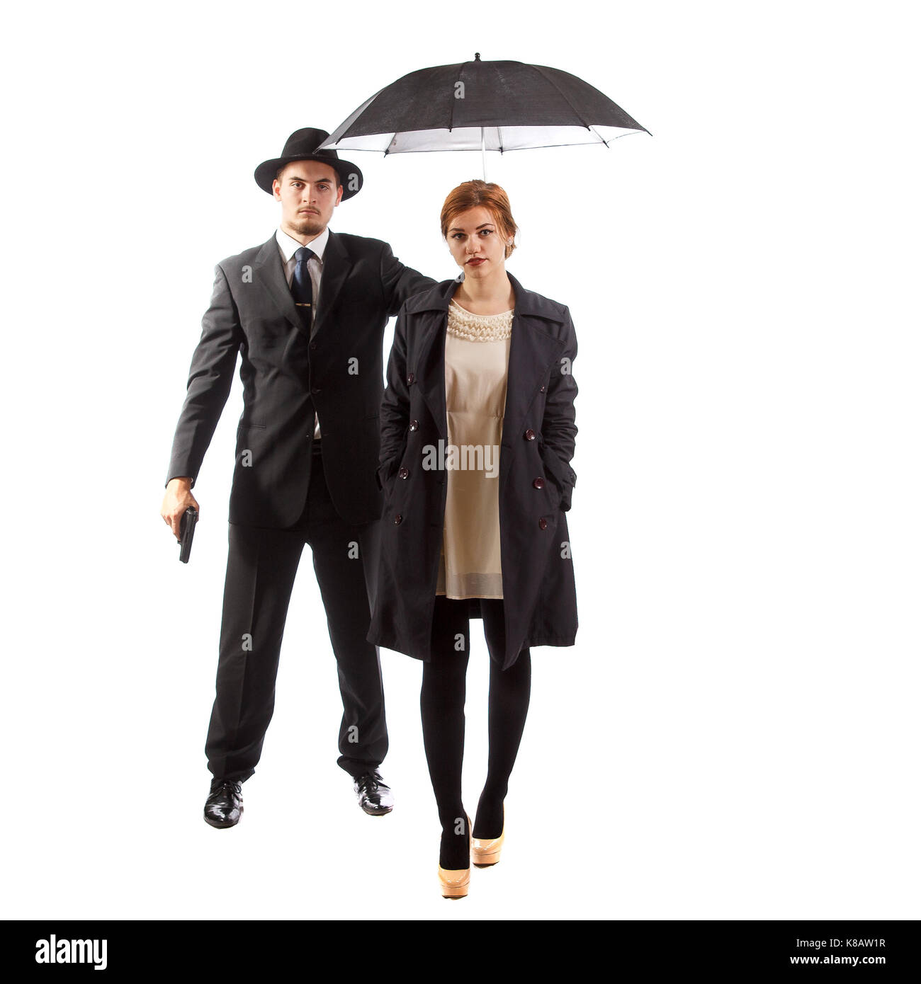 Une dame d'être escorté par un homme en costume tenant un pistolet et un parapluie Banque D'Images