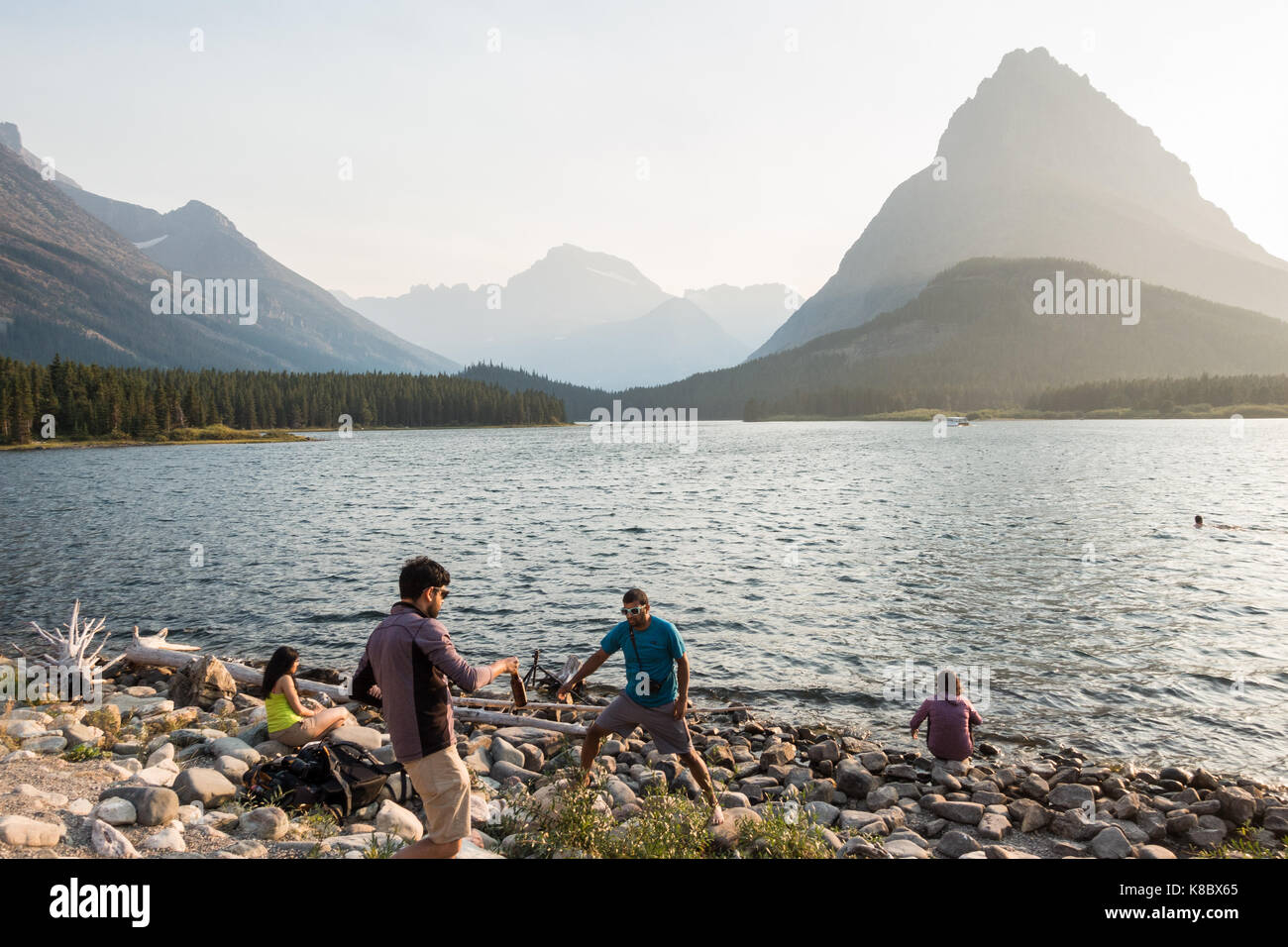 Les jeunes hommes profiter de la fin de l'après-midi au bord de la rive / swiftcurrent Lake dans le parc national des Glaciers Banque D'Images