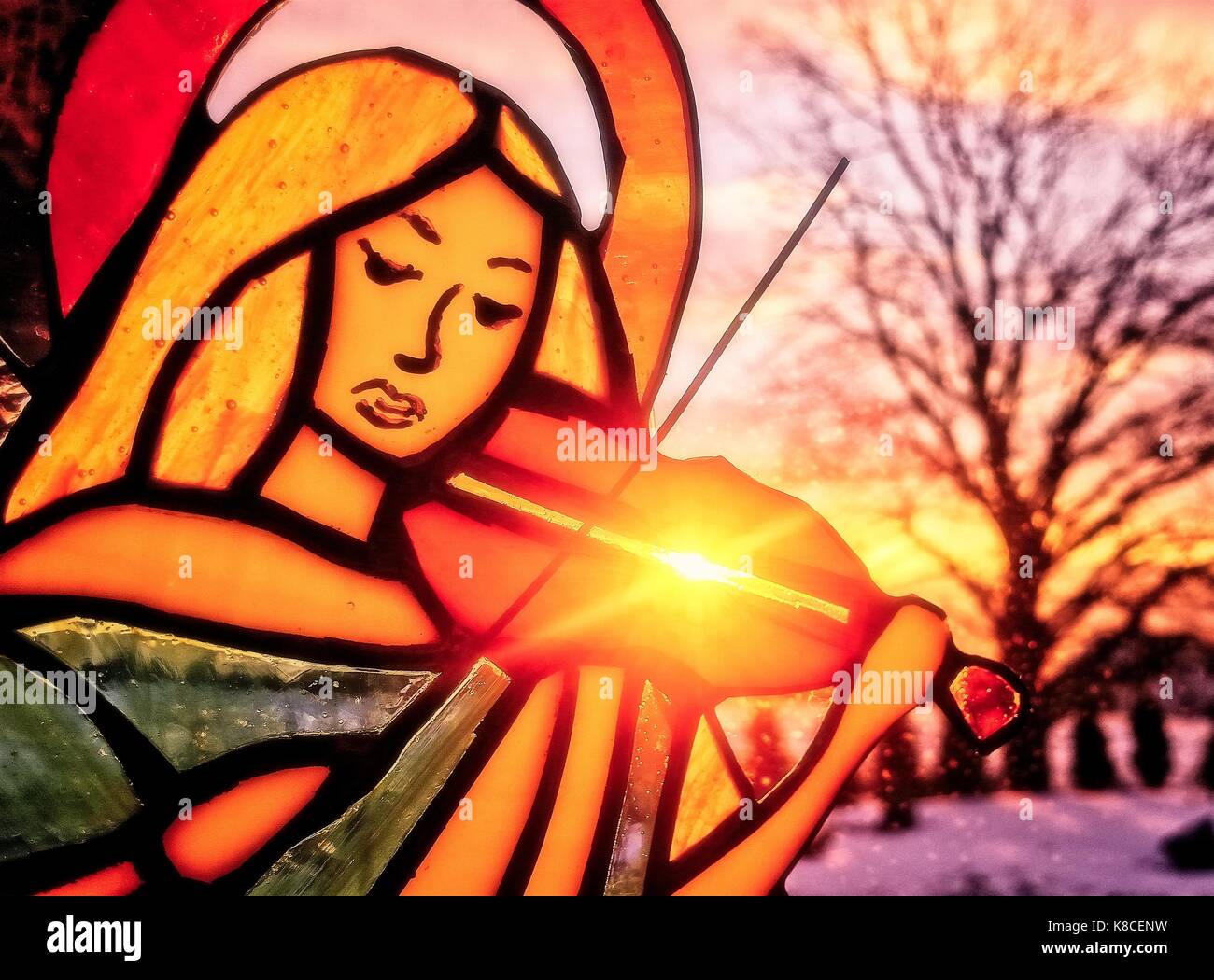 Un ange jouant du violon. Vitraux ange. Fond d'hiver. Paysages colorés. Soleil qui brille à travers le vitrail. Banque D'Images