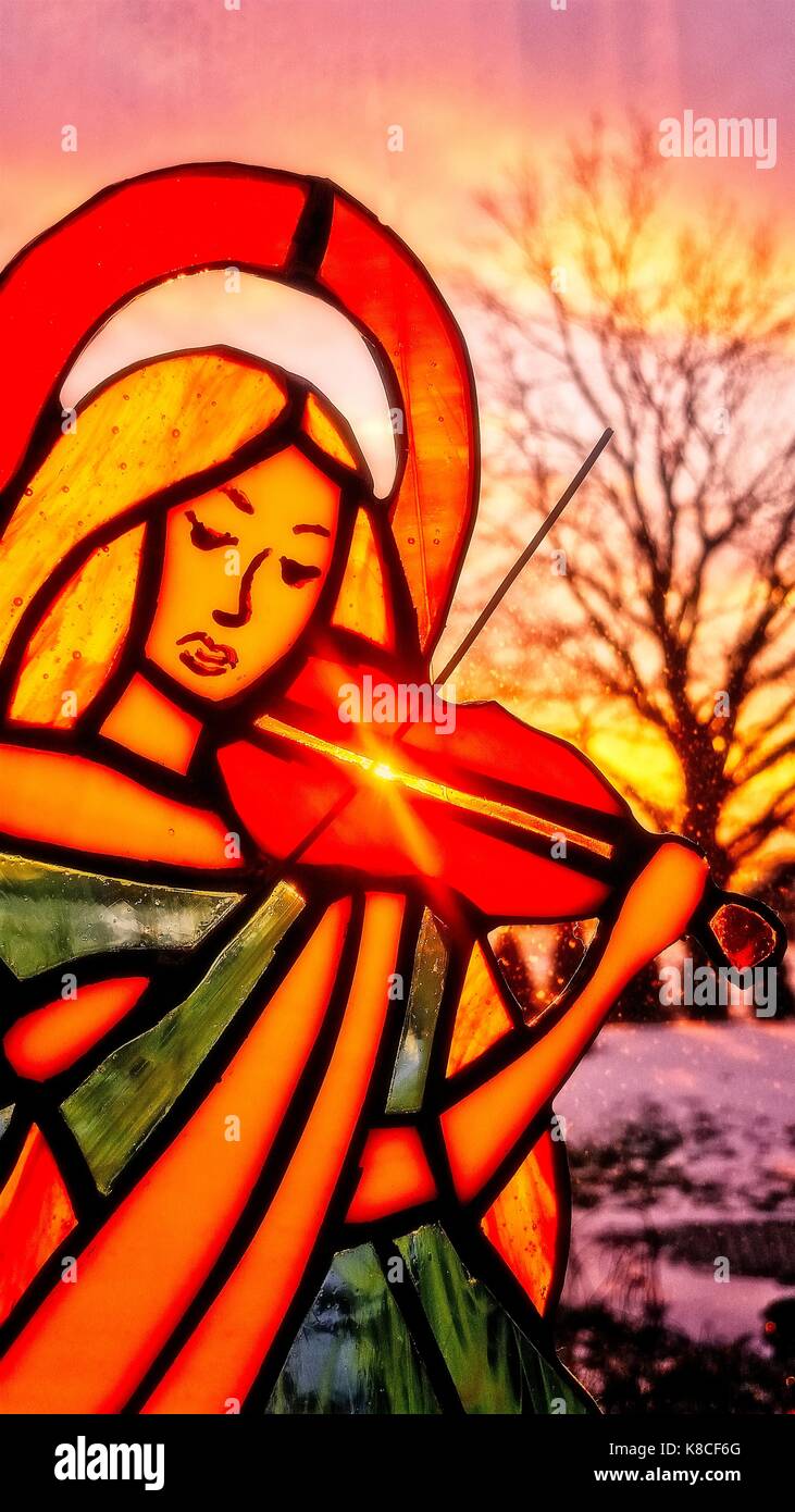 Un ange jouant du violon. Vitraux ange. Fond d'hiver. Paysages colorés. Soleil qui brille à travers le vitrail. Banque D'Images