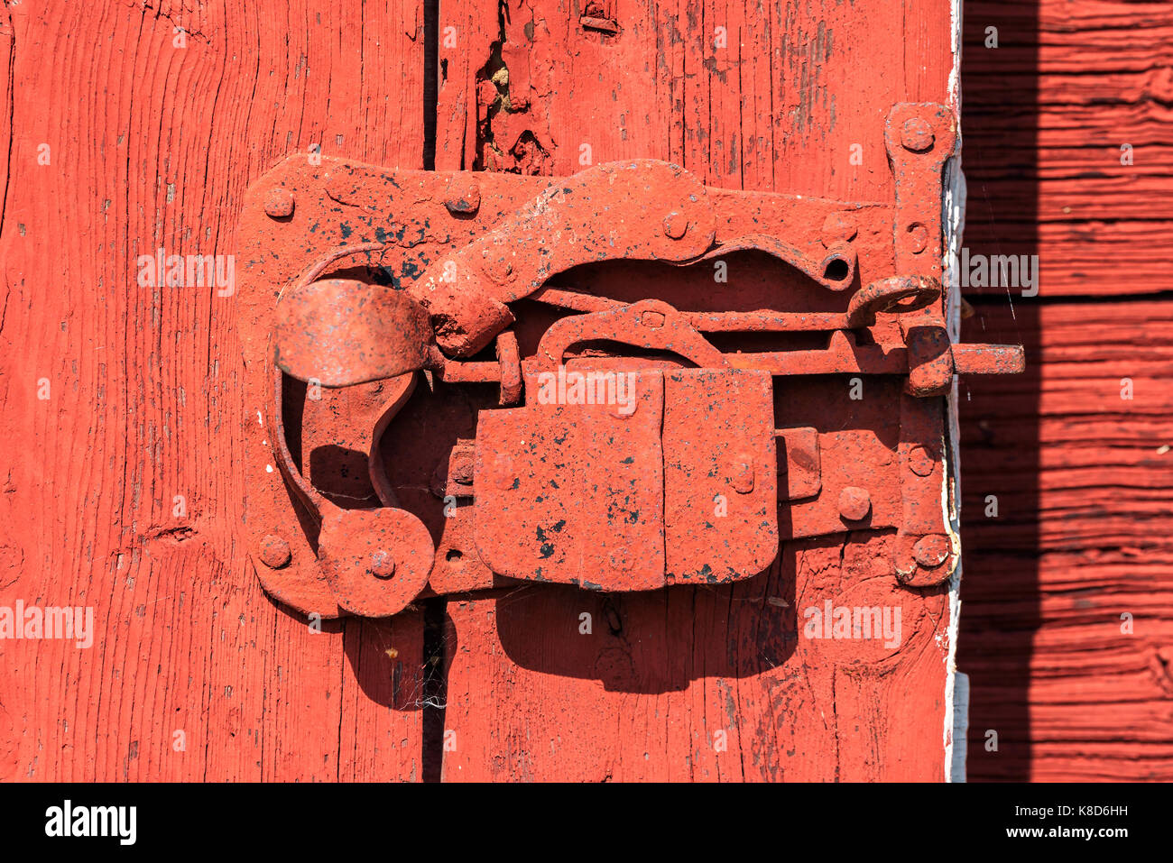 Mécanisme de verrouillage de la vieille couverte de peinture rouge sur une porte de grange. Banque D'Images