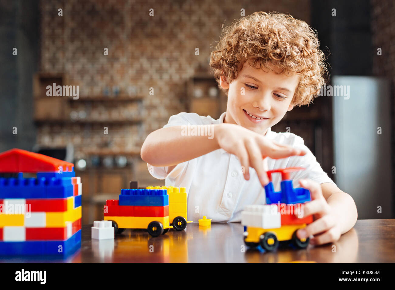 Garçon aux cheveux bouclés mignon construire sa voiture de rêve Banque D'Images