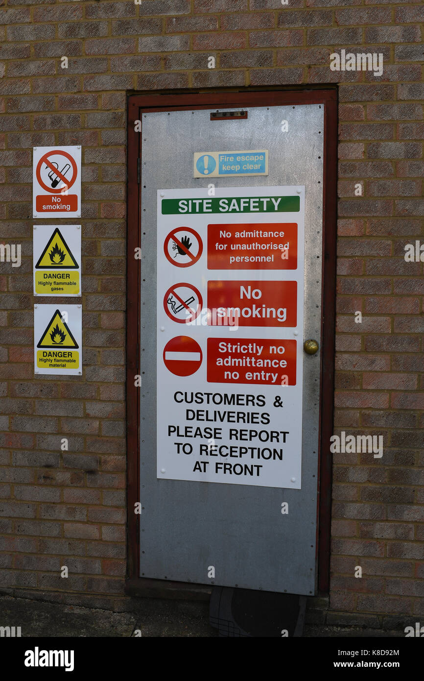 Une porte coupe-feu sécurisé sur une unité industrielle avec des avertissements de sécurité du site et des affiches Banque D'Images