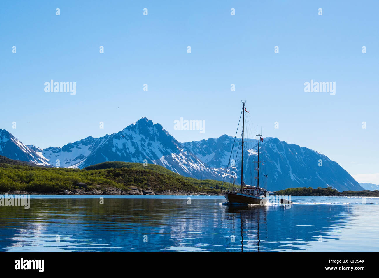 Voilier naviguant en eaux calmes au large de la côte du nord de la Norvège et Bjarkøya Helløya entre les îles. Bjarkøya, Troms, Norway, Scandinavia, Europe Banque D'Images