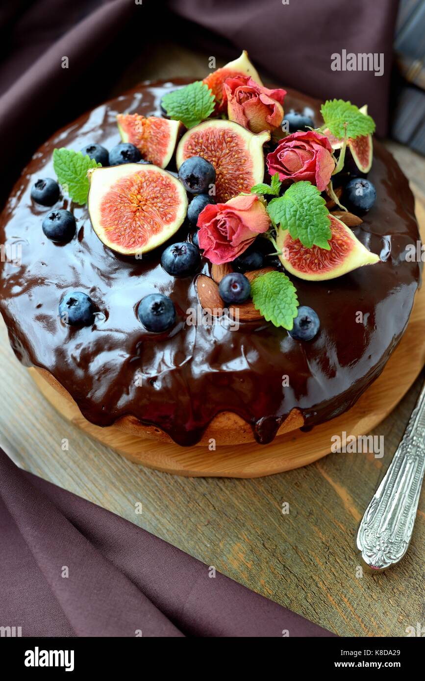 Сhocolate gâteau décoré avec des figues, baies, noix,menthe et roses Banque D'Images