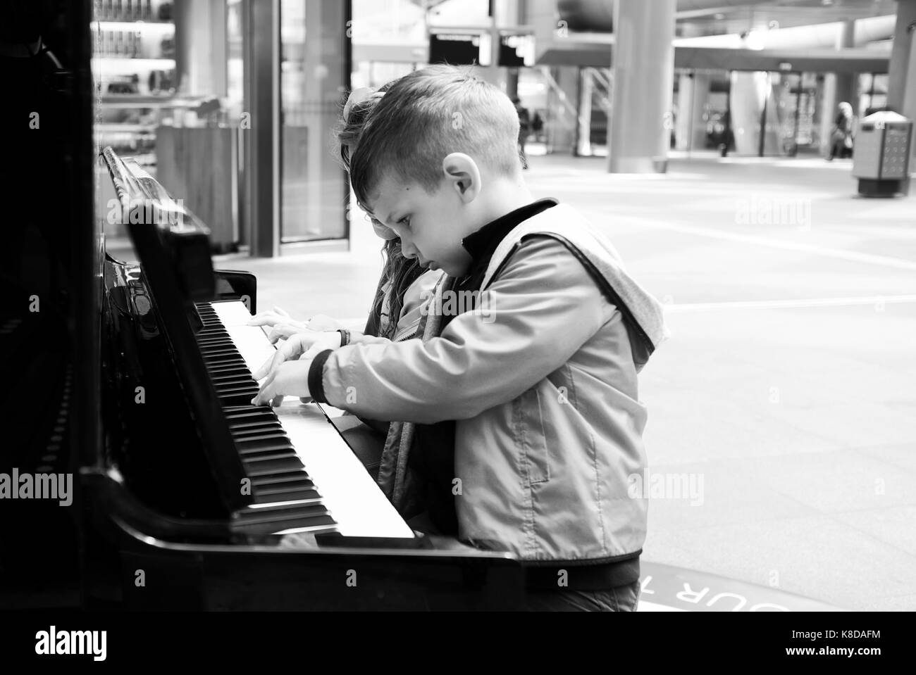 Petit Garçon jouant sur de vieux piano noir à l'extérieur Banque D'Images